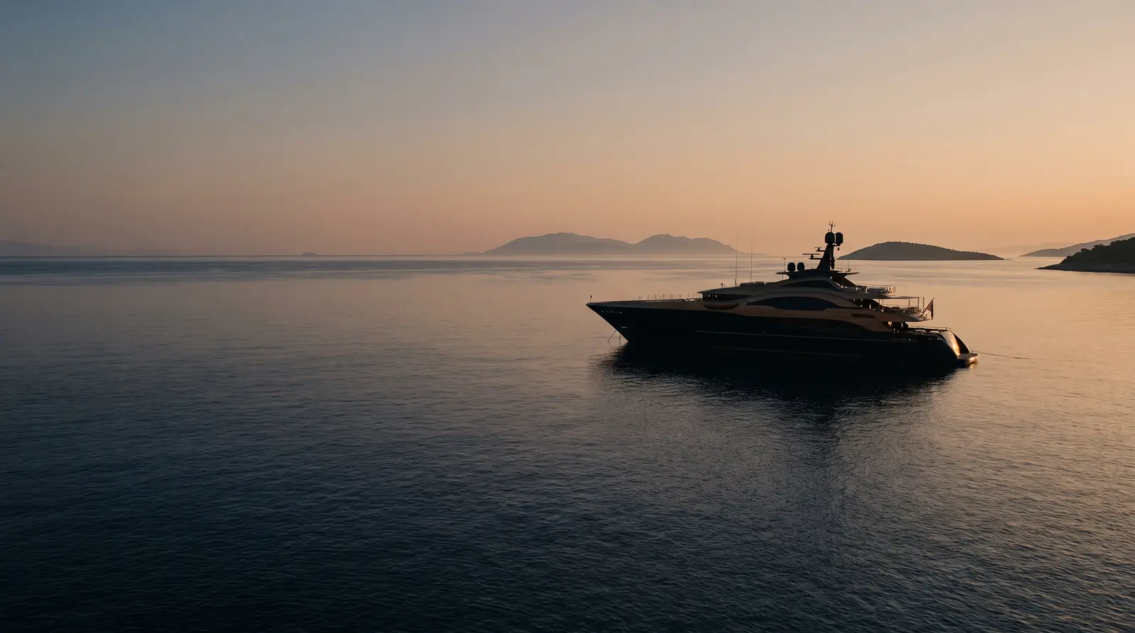 Superyacht at anchor in a Mediterranean bay at dawn