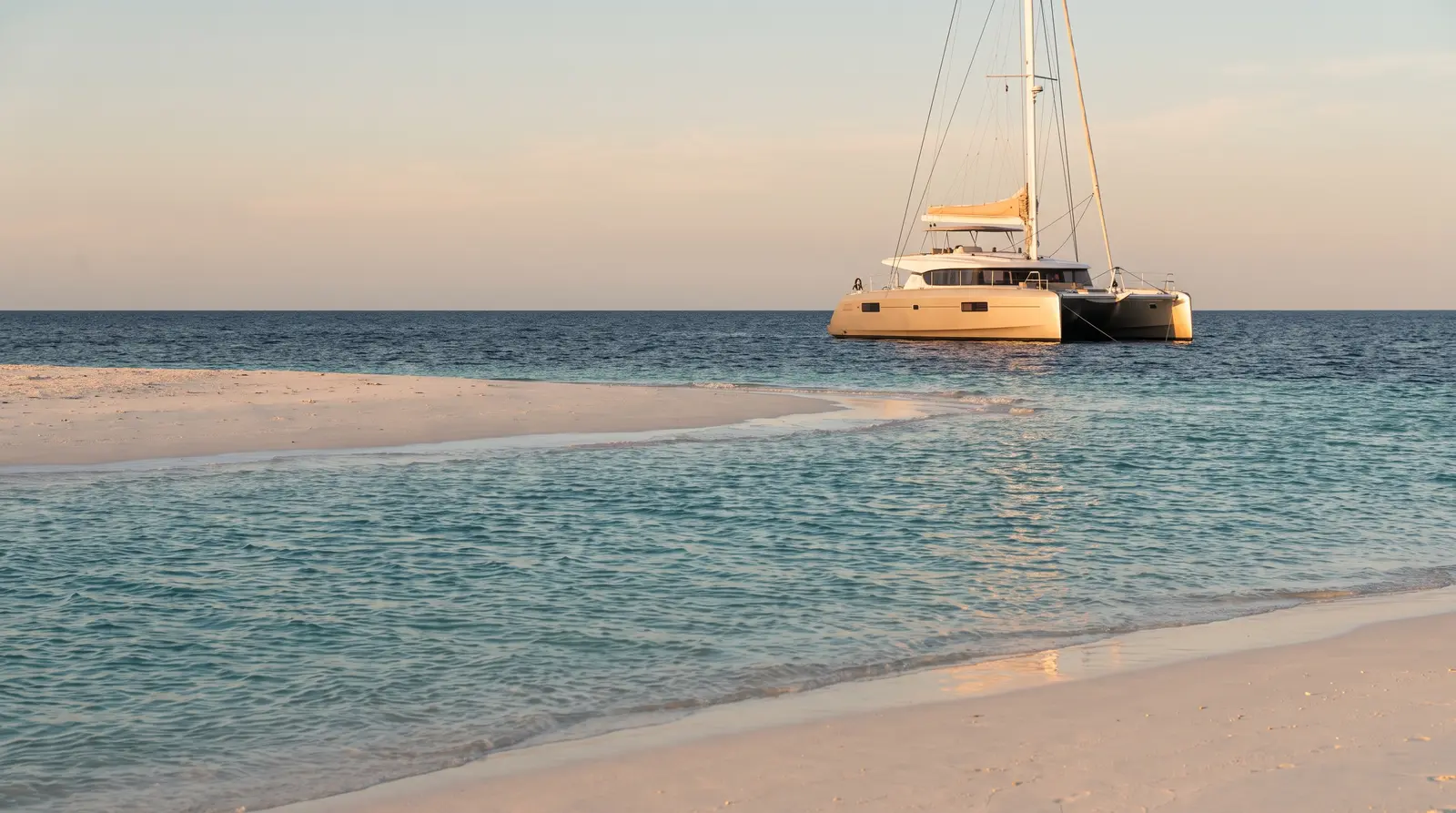 Catamaran anchored off an island beach