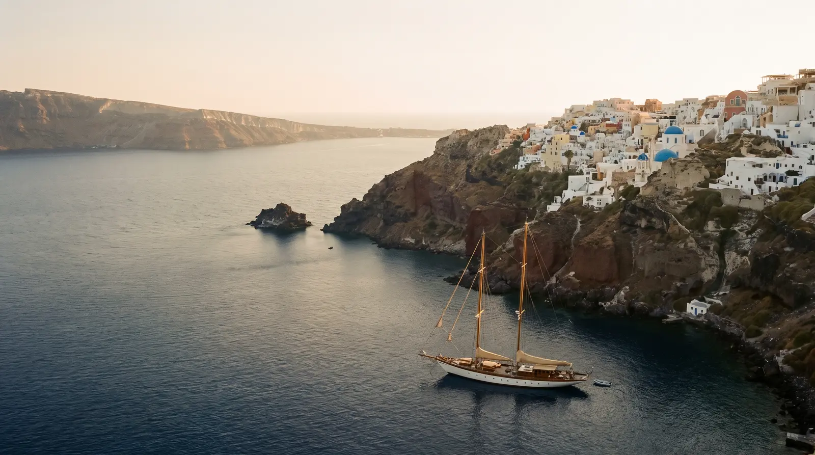 Sailing yacht anchored below a whitewashed Cycladic village