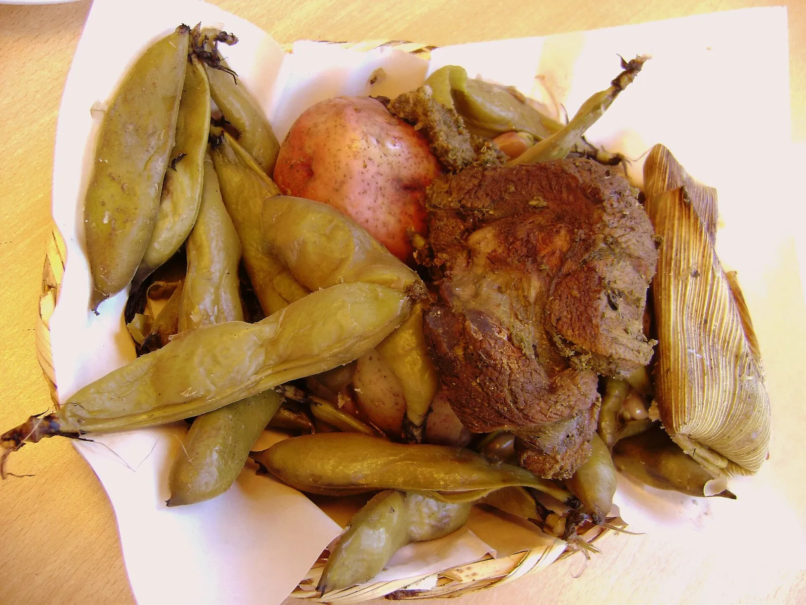 Pachamanca de carne com fava, batata e humita servida num prato
