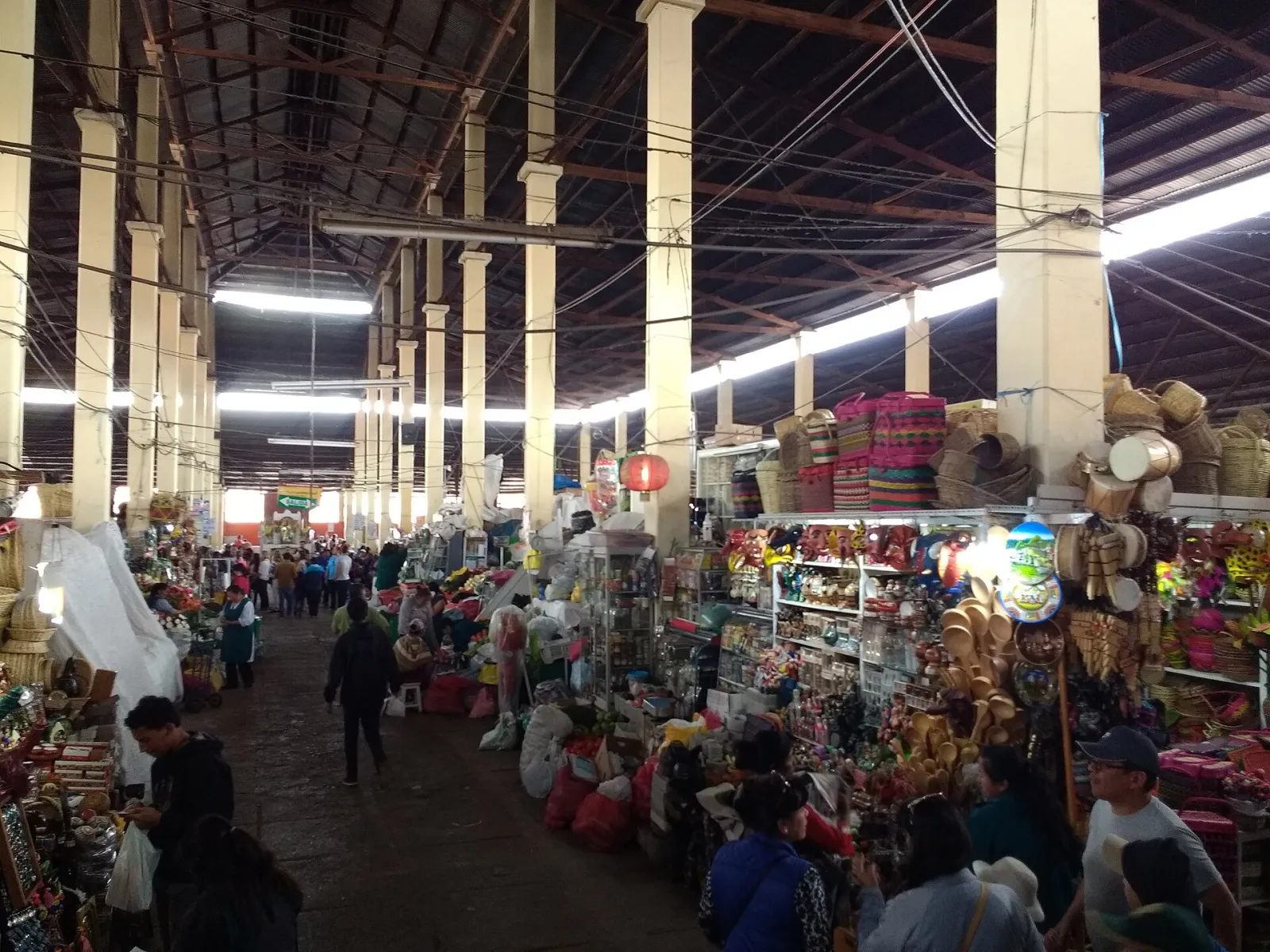 O longo corredor central do mercado San Pedro, em Cusco, com bancas sob um telhado alto