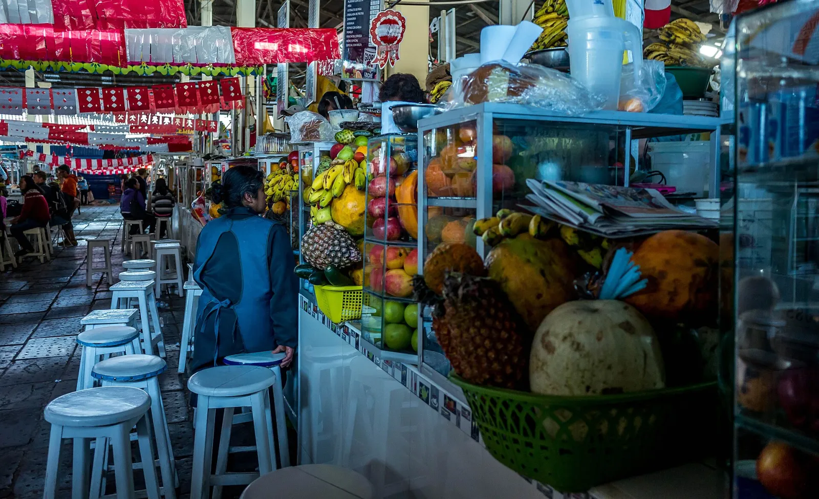 Fruit juice stalls with stools along the aisle inside San Pedro Market in Cusco