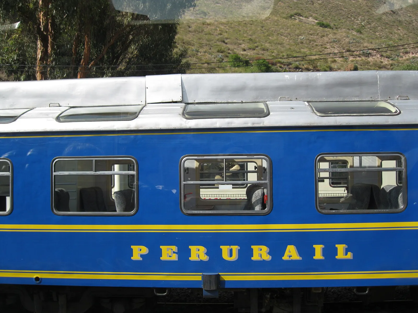 A blue PeruRail carriage with the company name in yellow letters