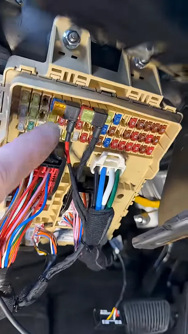 OEM ground bolt with red crimped ground lead and adjacent fuse box wiring in a Hyundai Tucson used for dash camera power.