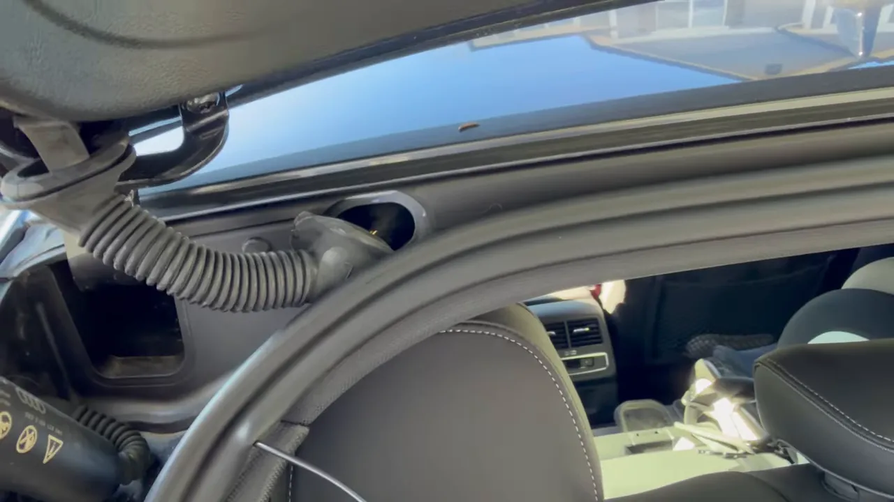 Dashcam wires routed under the hatch weatherstrip and through the factory pass-through hole on an Audi A5.