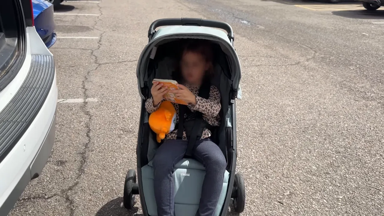 Toddler in Thule Spring 2 in mid blue outdoors in parking lot