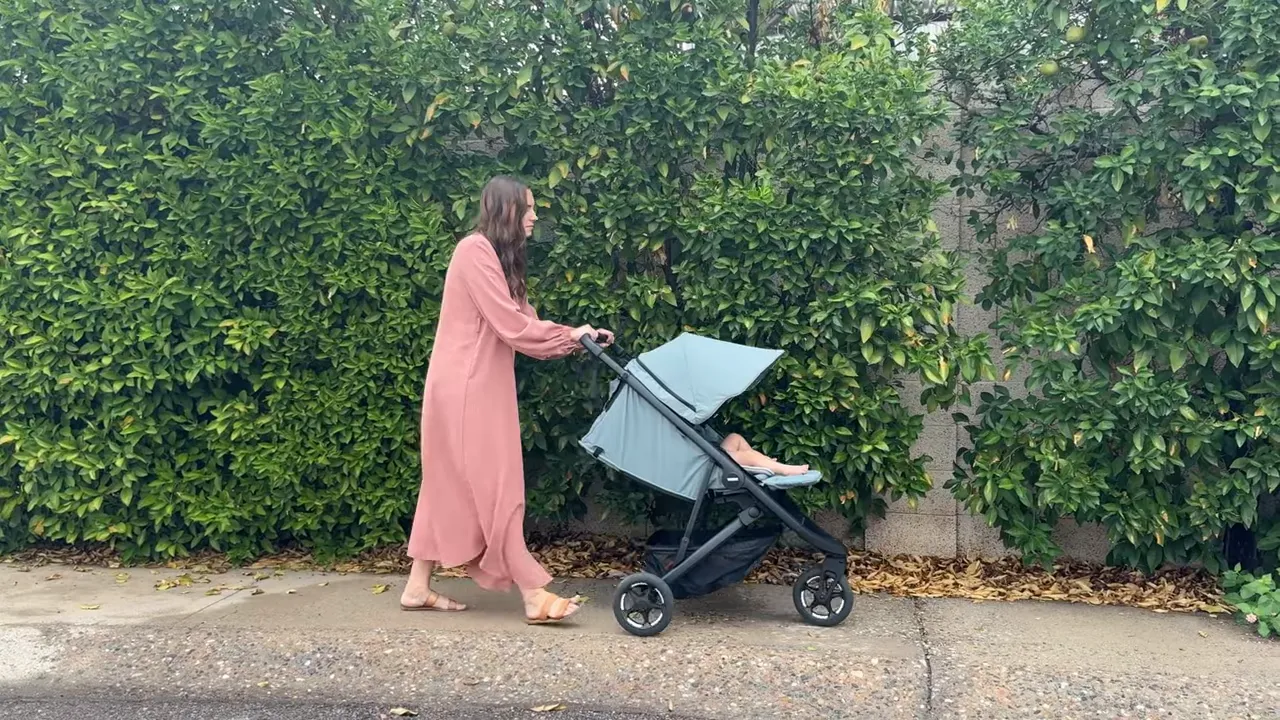Mom pushing Thule Spring 2 on sidewalk showing full canopy coverage and reclined seat