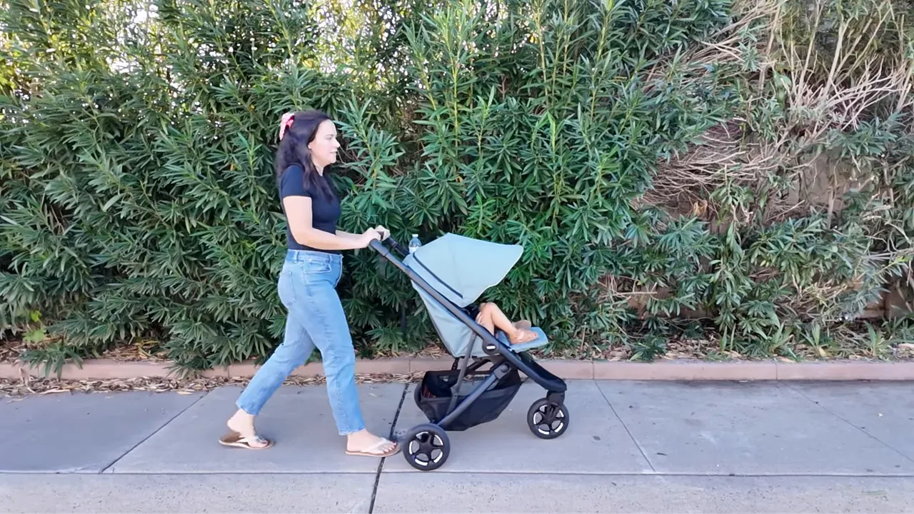 Mom pushing Thule Spring 2 on sidewalk with canopy partially extended
