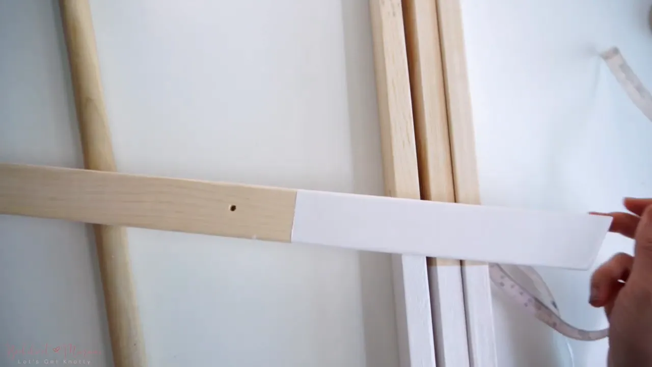 Hands holding a ruler on a wooden leg showing the top hole position (4.5 inches from the top).