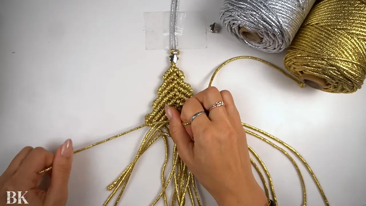 Overhead view of macrame tree with hands making horizontal double half hitch knots to gather the sides