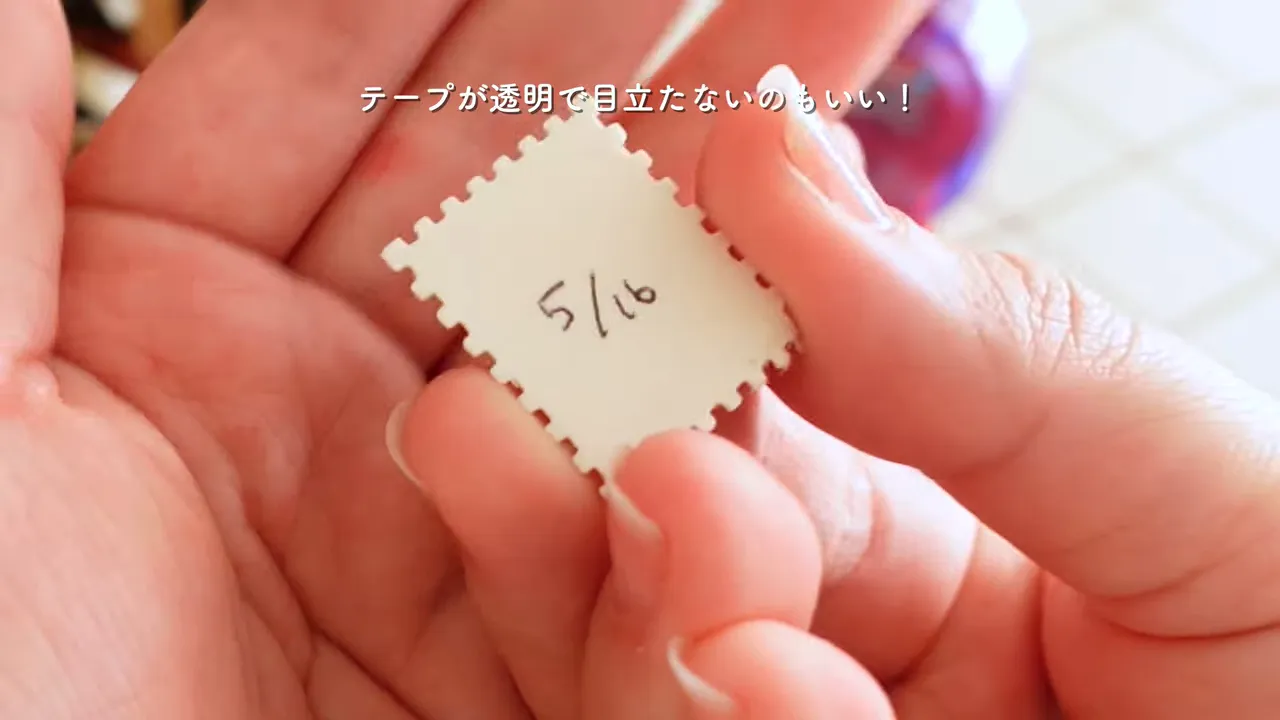 tesaスタンプのりで切手型の紙を指で位置合わせして貼る様子