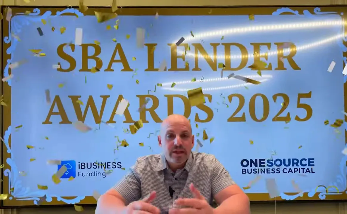 Speaker seated in front of a large screen reading 'SBA LENDER AWARDS 2025' with confetti overlay