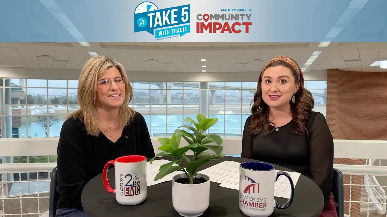 Both hosts smiling during the interview with a plant and branded mugs in foreground