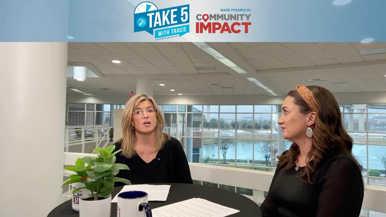 Two people seated across from each other at a small round table during a recorded interview about inclusion.