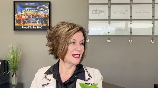 Katrina Kirkpatrick speaking in an office with a framed photo and wall display behind her