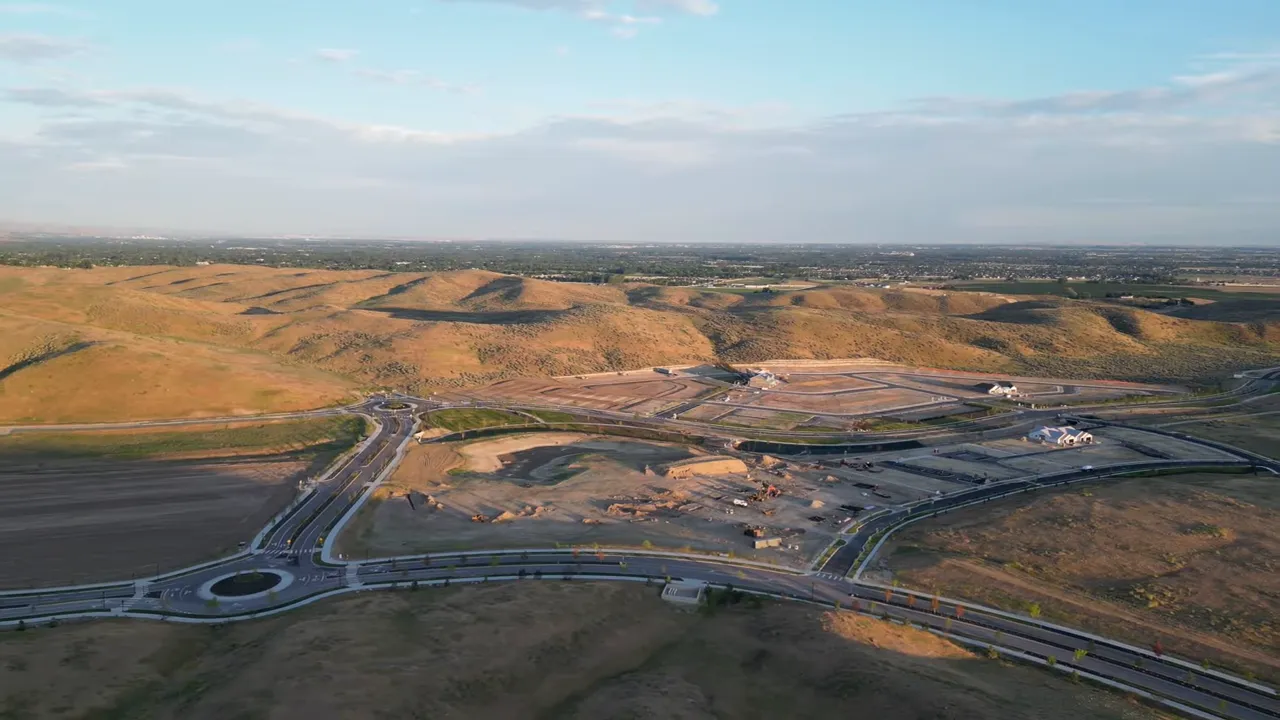 Aerial drone view of new construction single-family homes, vacant lots and foothills in the background