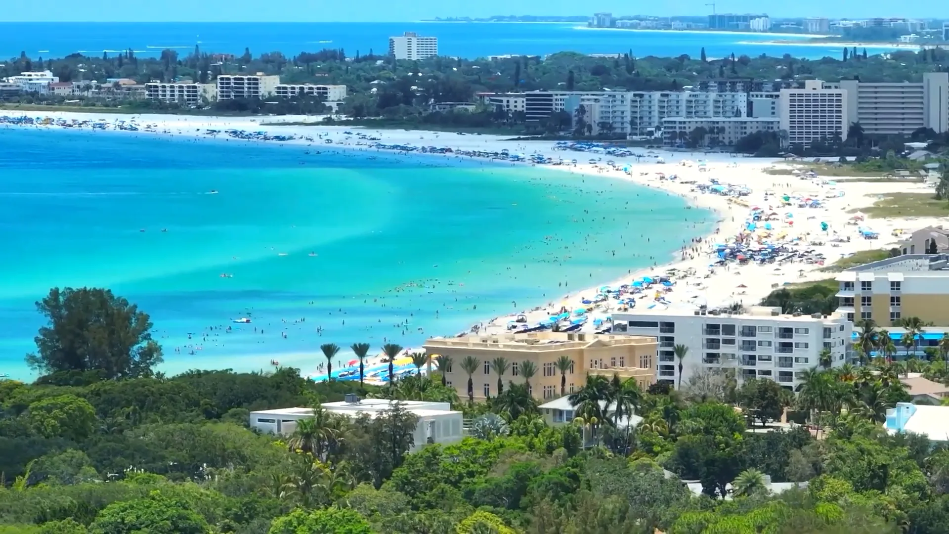 Siesta Beach wide sand and beachgoers with blue umbrellas