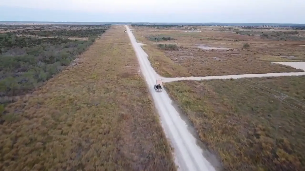 Aerial shot showing a long dirt road and surrounding parcels on the plains.