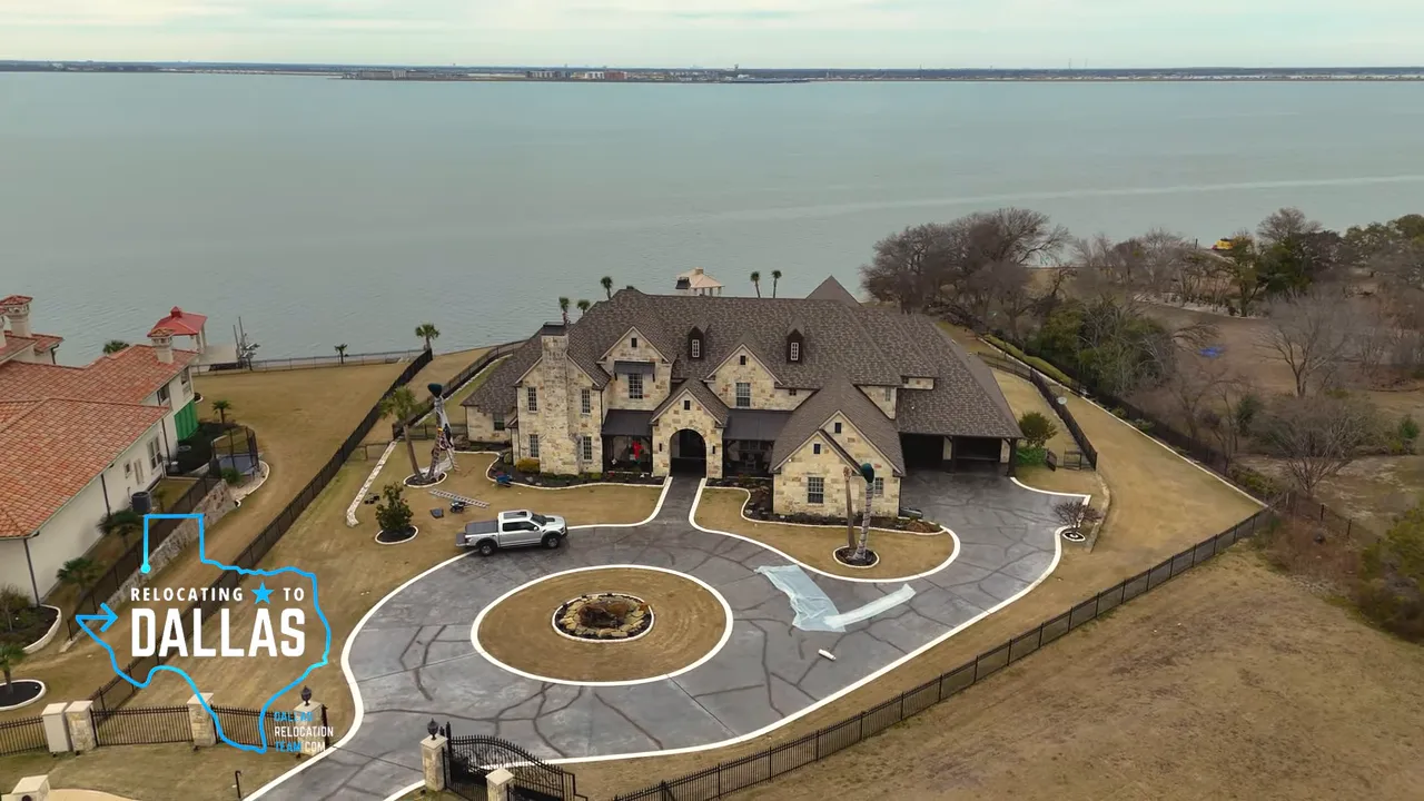 Clear front view of a large stone lakefront mansion with gated entrance and circular driveway