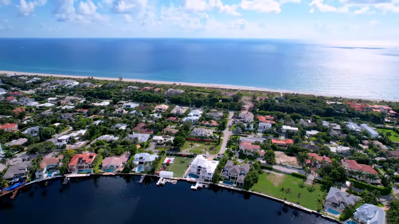 Stone and water entrance sign reading 'SEAGATE COUNTRY CLUB AT THE HAMLET' with manicured flowers and palm trees