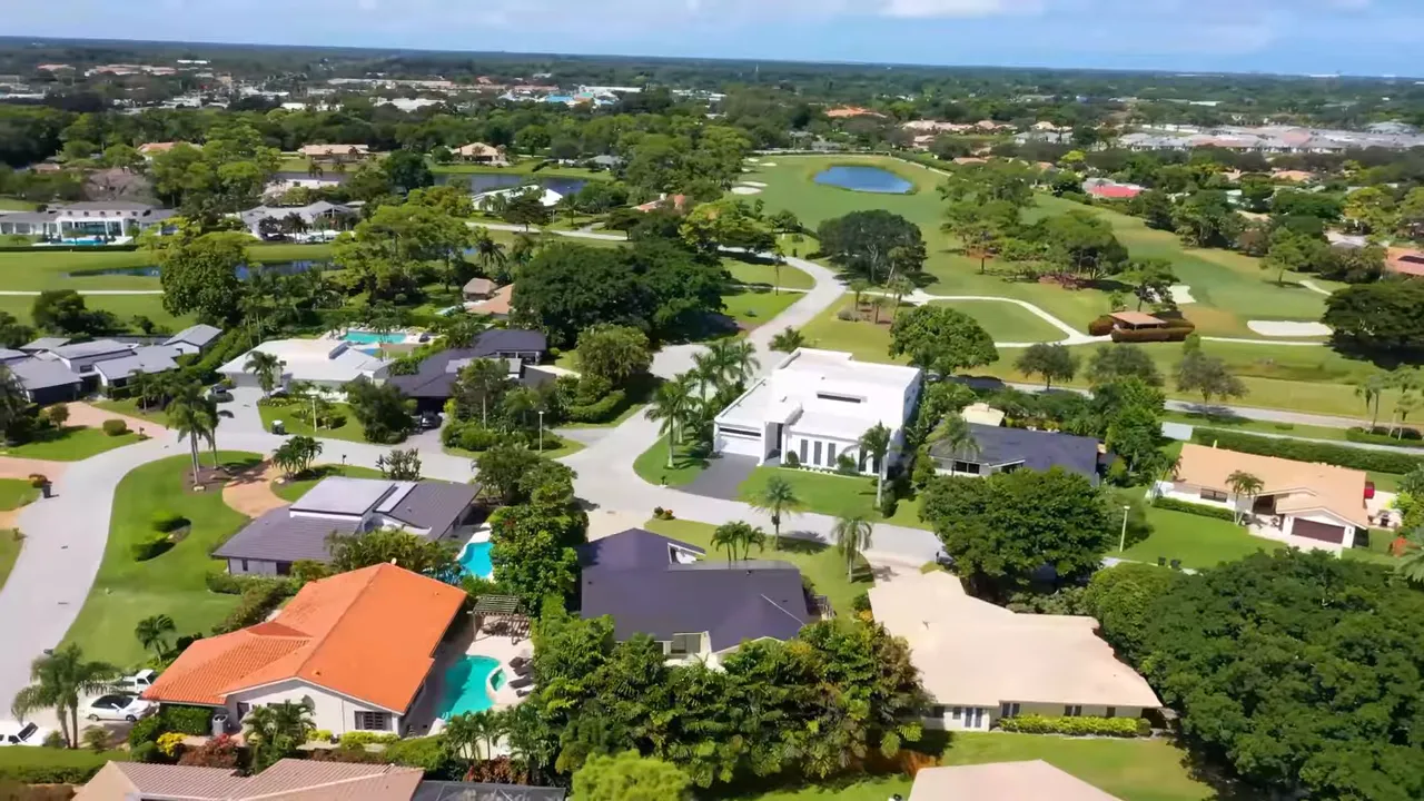 Aerial drone view of a large Mediterranean-style estate with tiled roofs, pool, and palm trees.