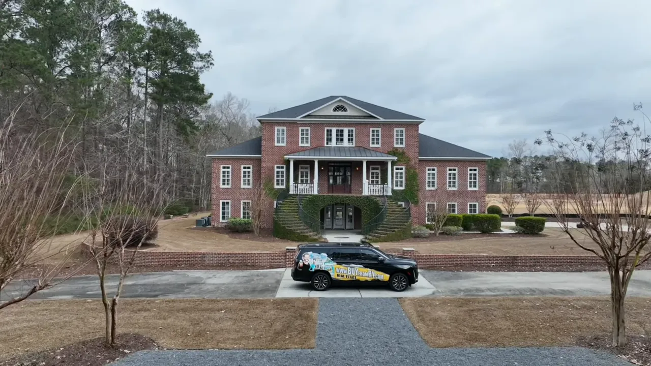 Aerial view from the front porch showing curved brick steps, wrought-iron railing, split driveway and parked SUV