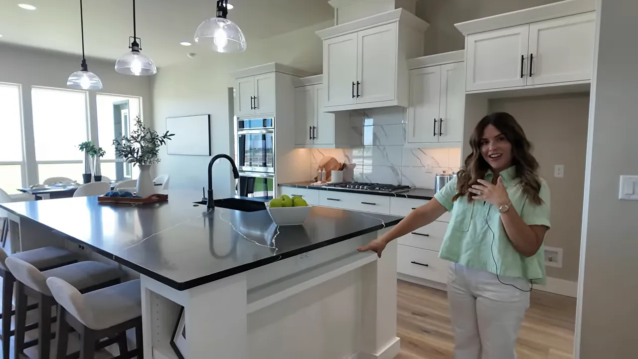 Large kitchen island with black countertop white cabinets and bar stools