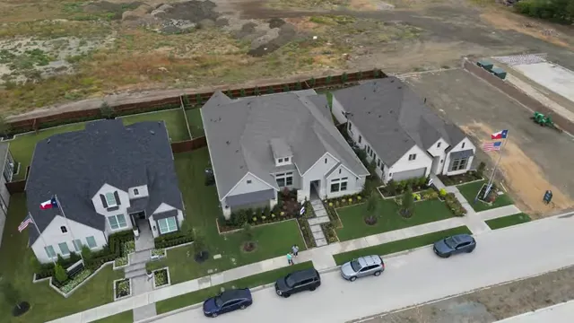 Aerial view of developing neighborhood streets, home sites, and nearby completed homes