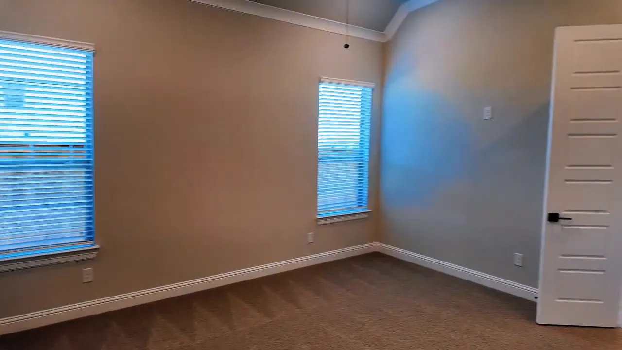 Hand adjusting a thermostat in the primary bedroom of a new construction home near Dallas, Texas