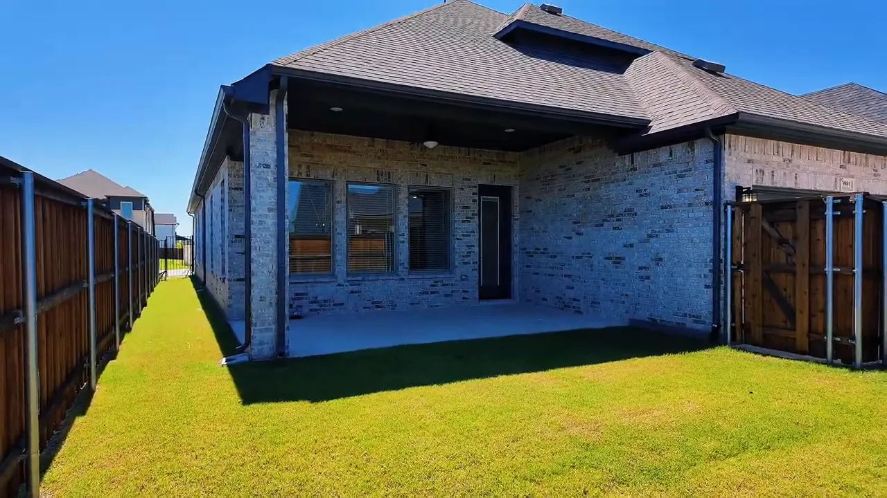 Rear yard view showing fenced backyard area and gutter line on a new construction home near Dallas