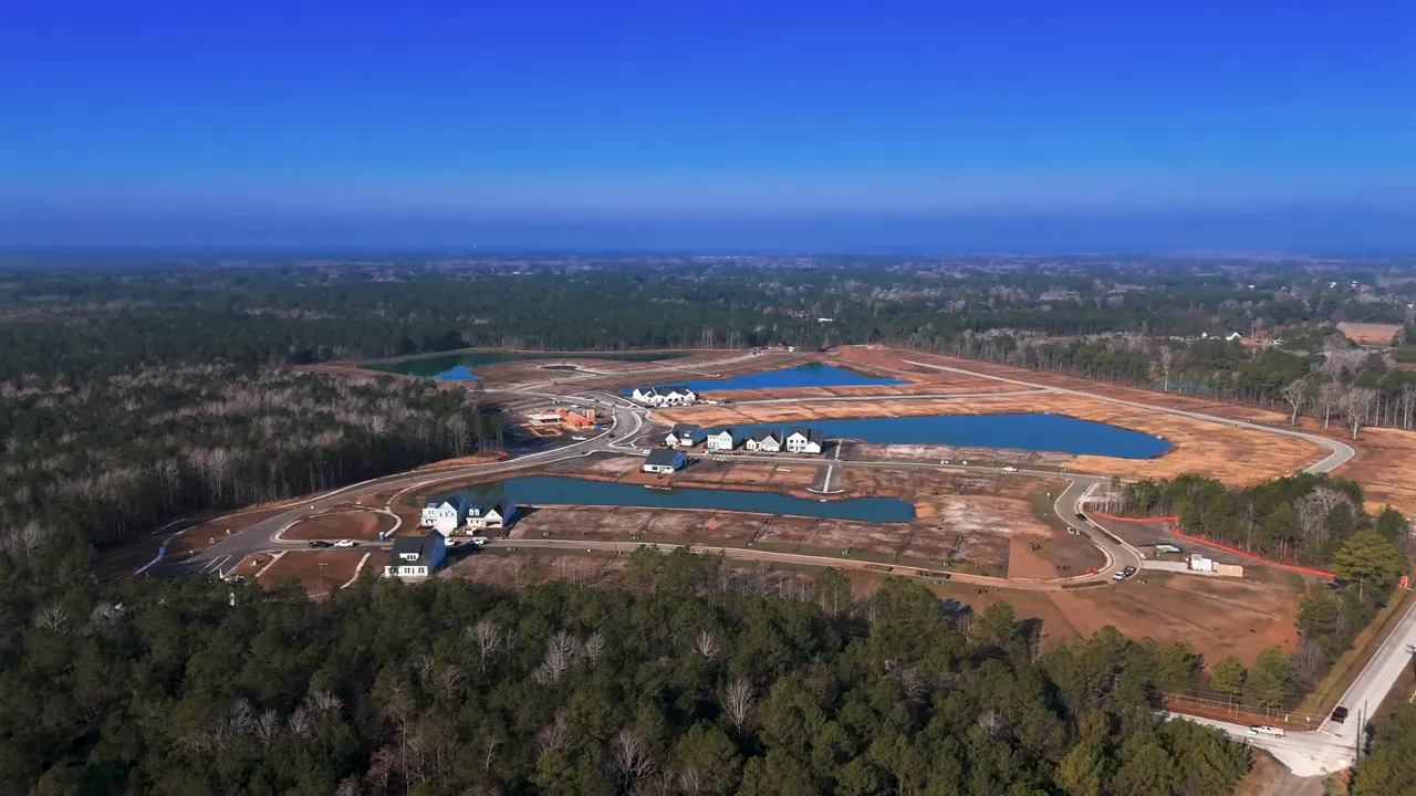Home entry showing architectural exposed beams, covered porch chairs, concrete walkway and planted beds