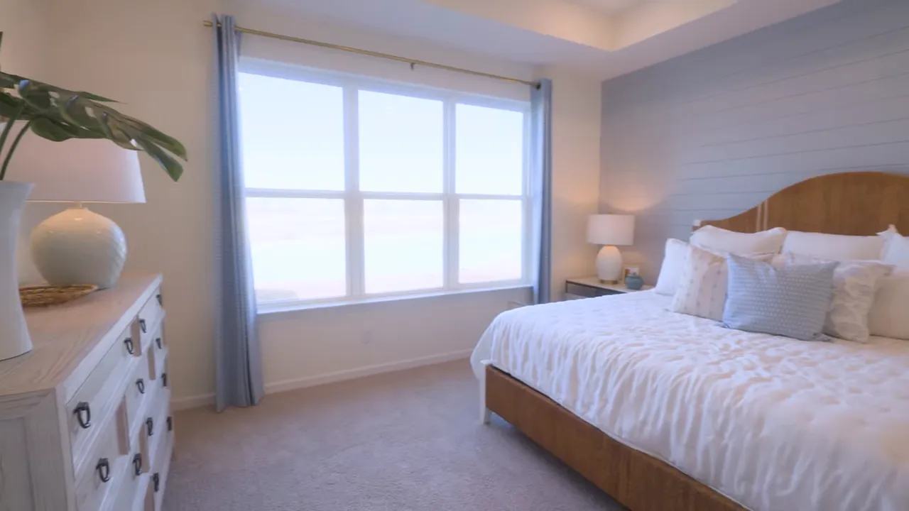 Primary bedroom with large six-pane window, tray ceiling, dresser and bedside lamp