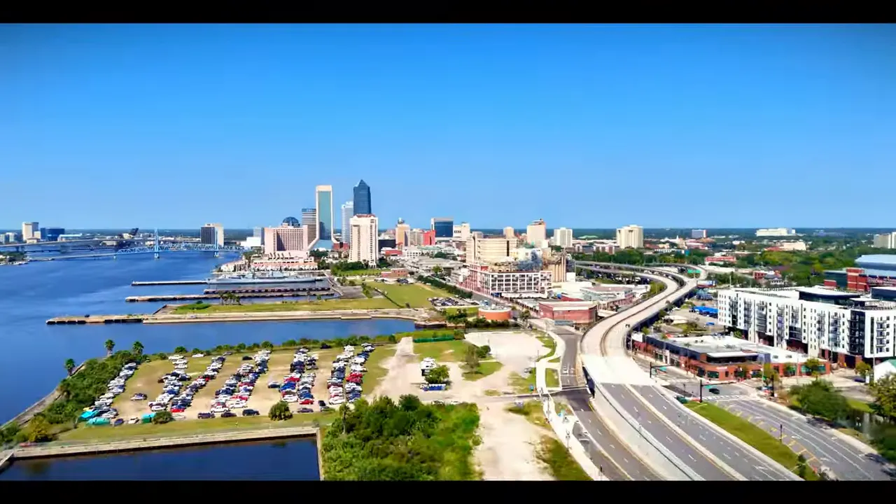 Presenter standing on a wide new sidewalk in front of modern townhomes and street trees in redeveloped downtown Jacksonville.