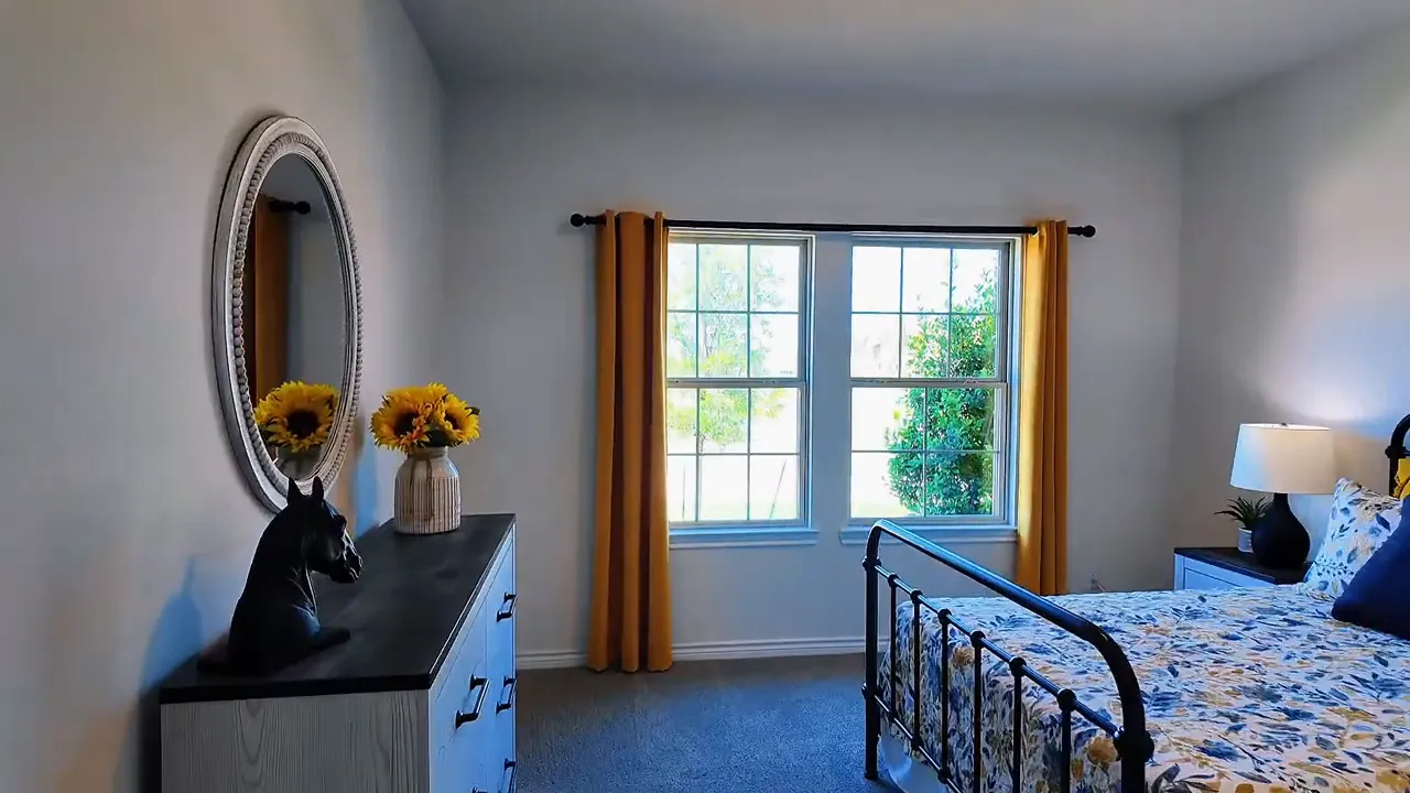 Bright front bedroom with large windows and curtains in a new construction home