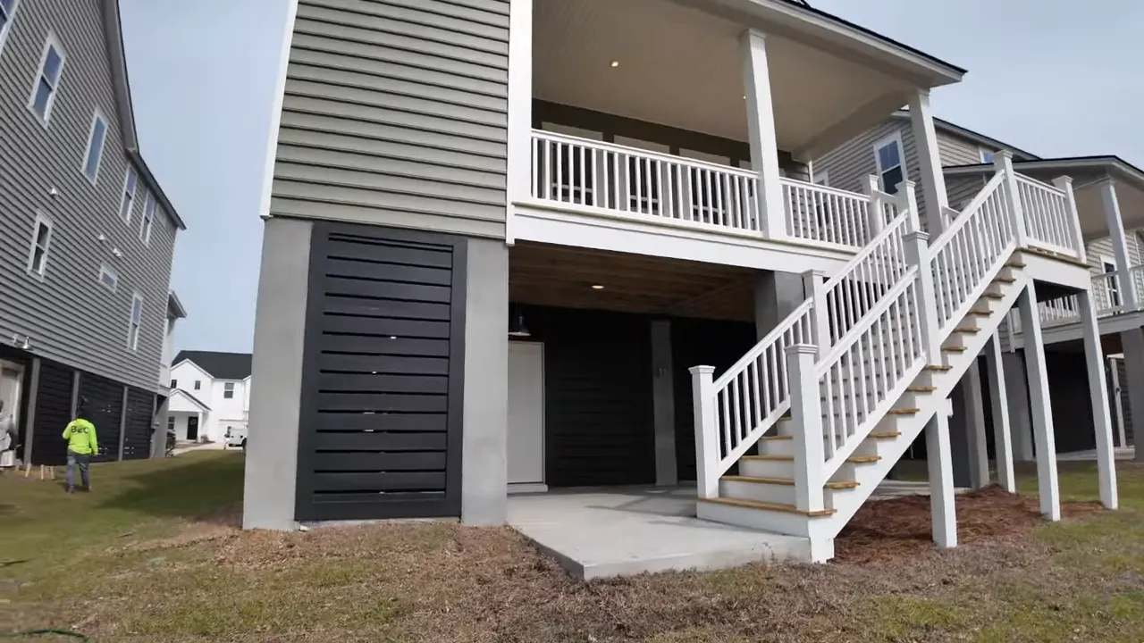 Realtor speaking on the covered porch overlooking the yard at an elevated new construction home in Summers Corner, SC