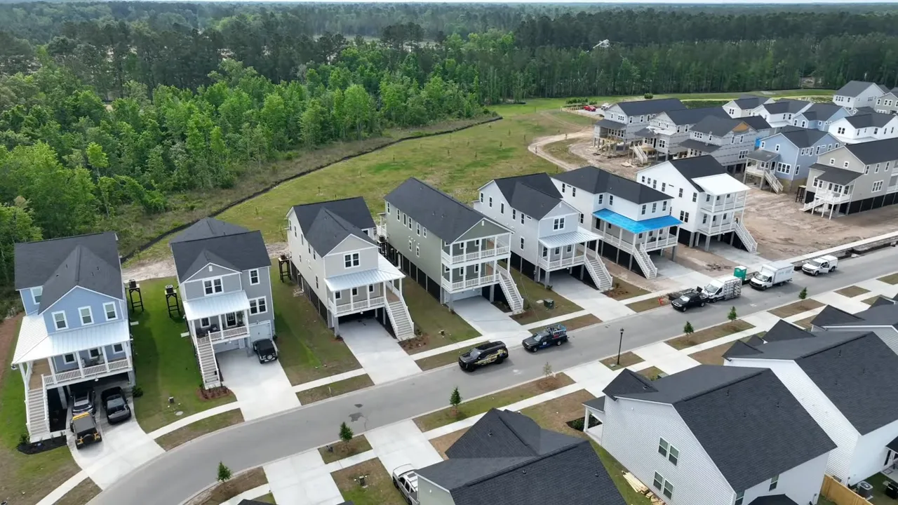 New construction home exterior with elevated front porch and multi-vehicle driveway in Summers Corner, South Carolina
