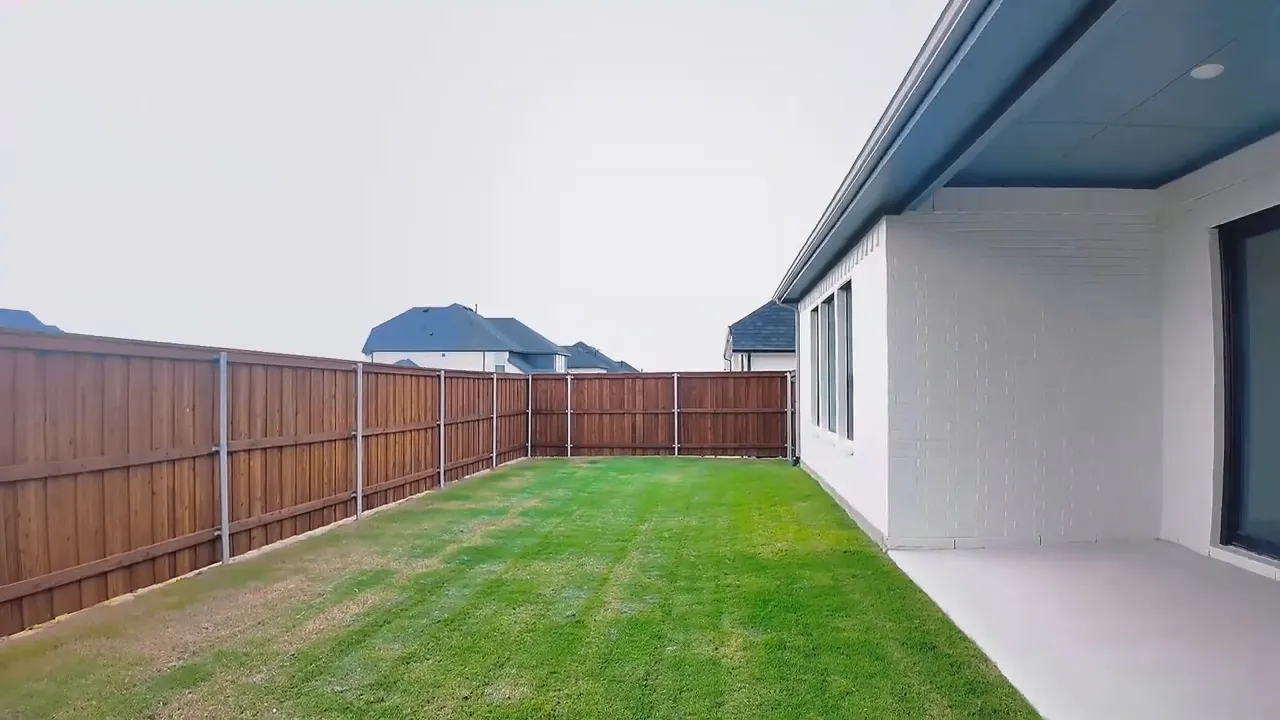 Covered patio with white columns fenced backyard and grass lawn