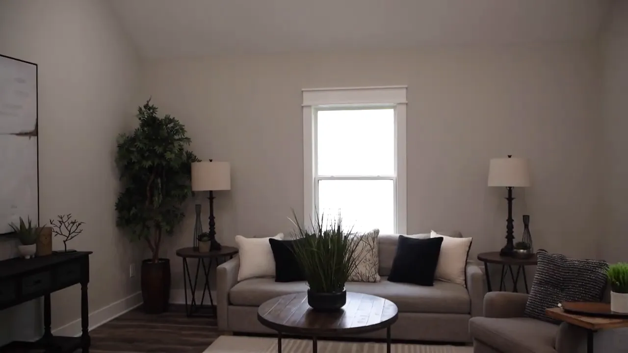 Living room with vaulted ceiling, sofa, chairs, and tall central window