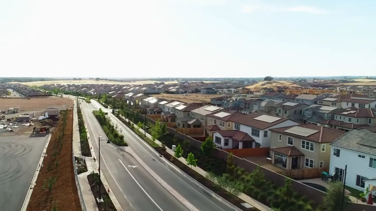 Drone shot of newly built single-family homes with adjacent construction pads in a master-planned neighborhood