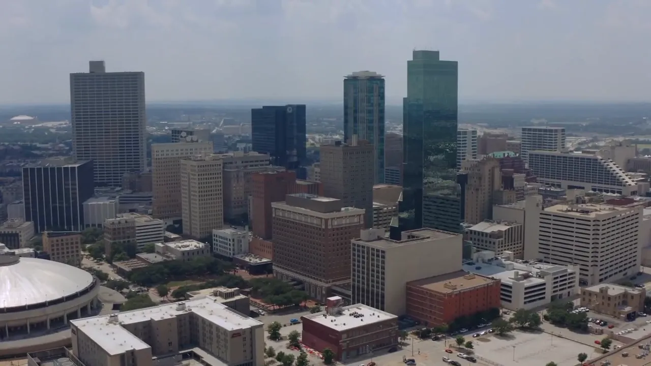 Presenter speaking in a well‑lit studio with microphone and motivational posters in the background, mid‑gesture