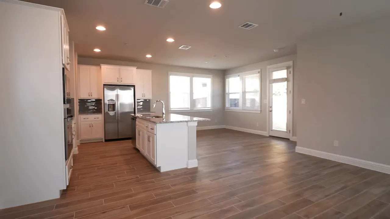 Empty open living room and kitchen area with staircase and ceiling fan
