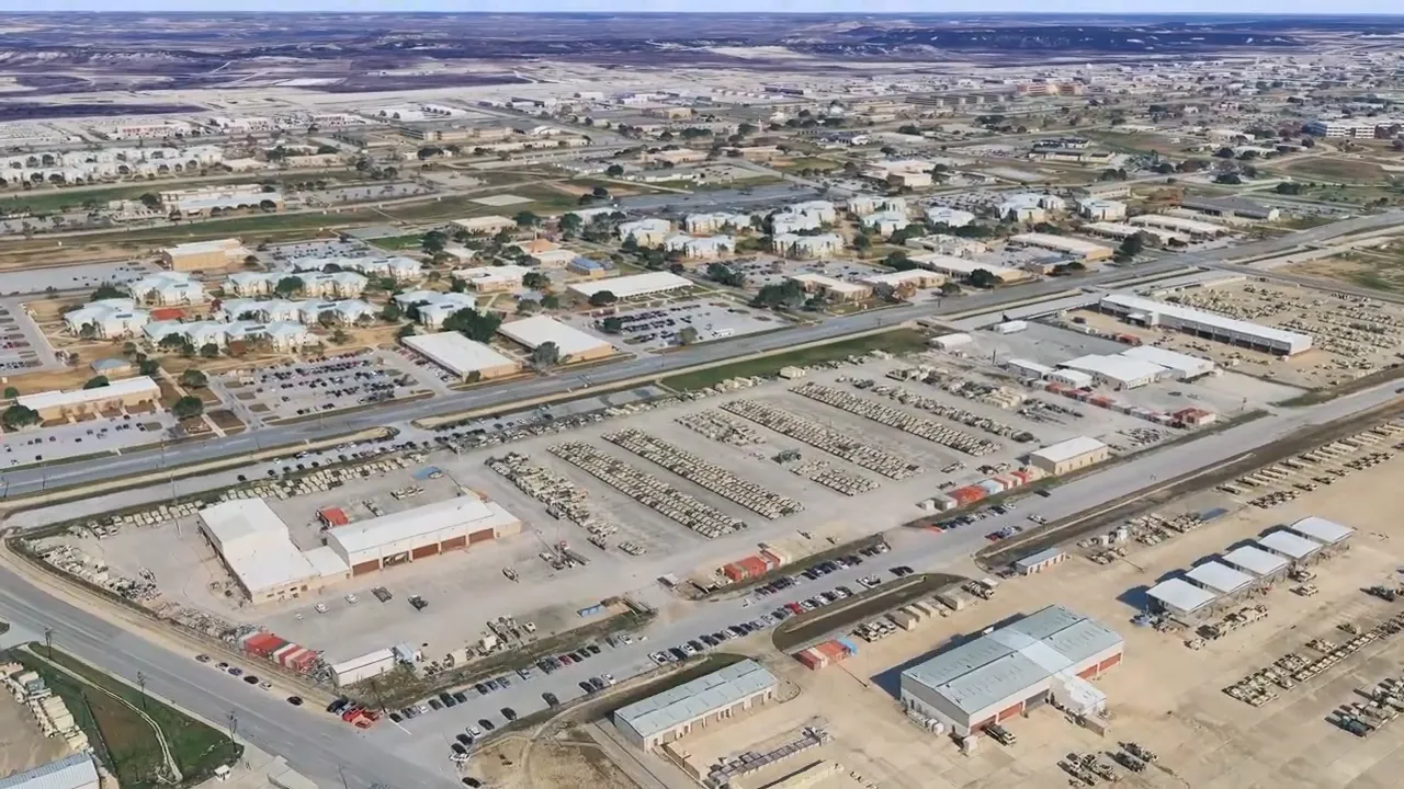 Model home kitchen showing dark wood range hood, two-toned island, tiled backsplash and a presenter at right