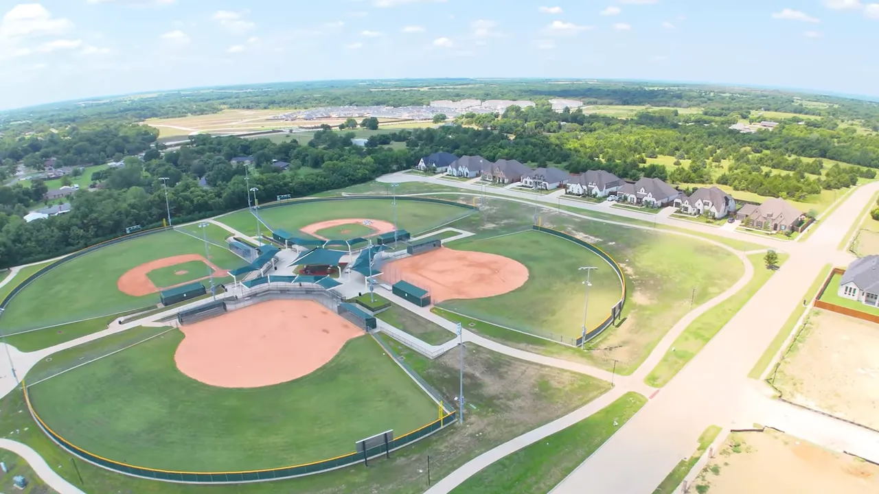 Presenter looking reflective into camera with a pink slatted wall behind and a microphone in front.