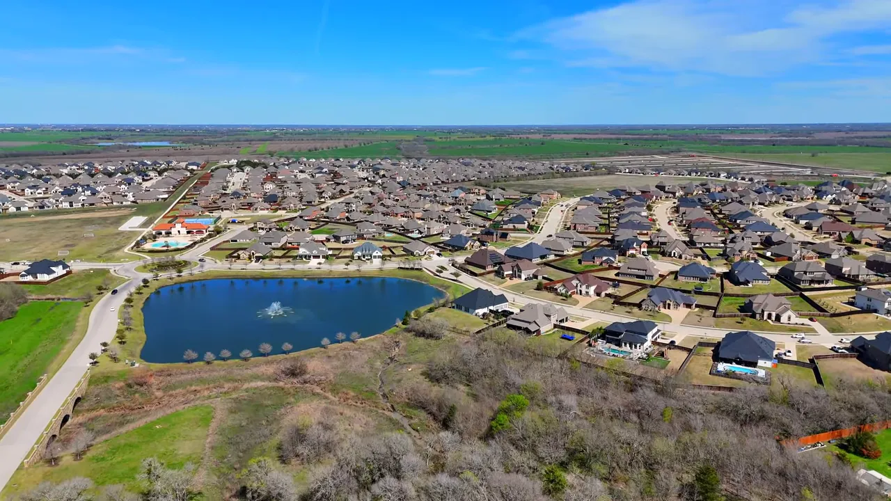 Wide aerial view of a model home and neighborhood street illustrating lot size and curb appeal