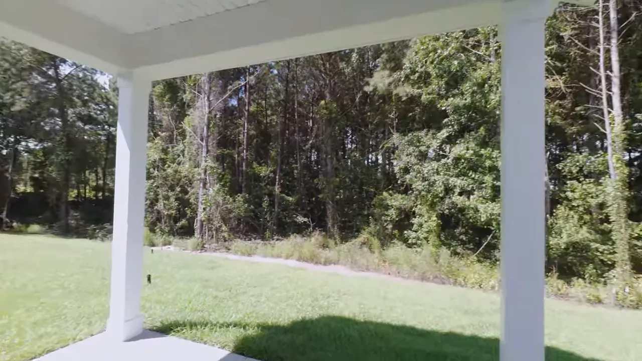 Covered porch area with a clear view of the yard and wooded background in a Little River SC new construction home