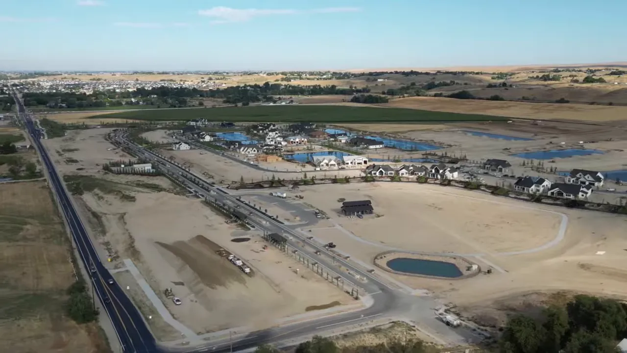 Presenter standing in front of a Terra View lake with homes, beach, and landscaped shoreline in the background