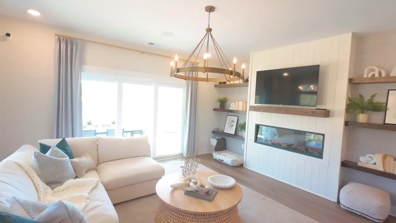 Living room with sectional sofa electric fireplace floating shelves and large windows