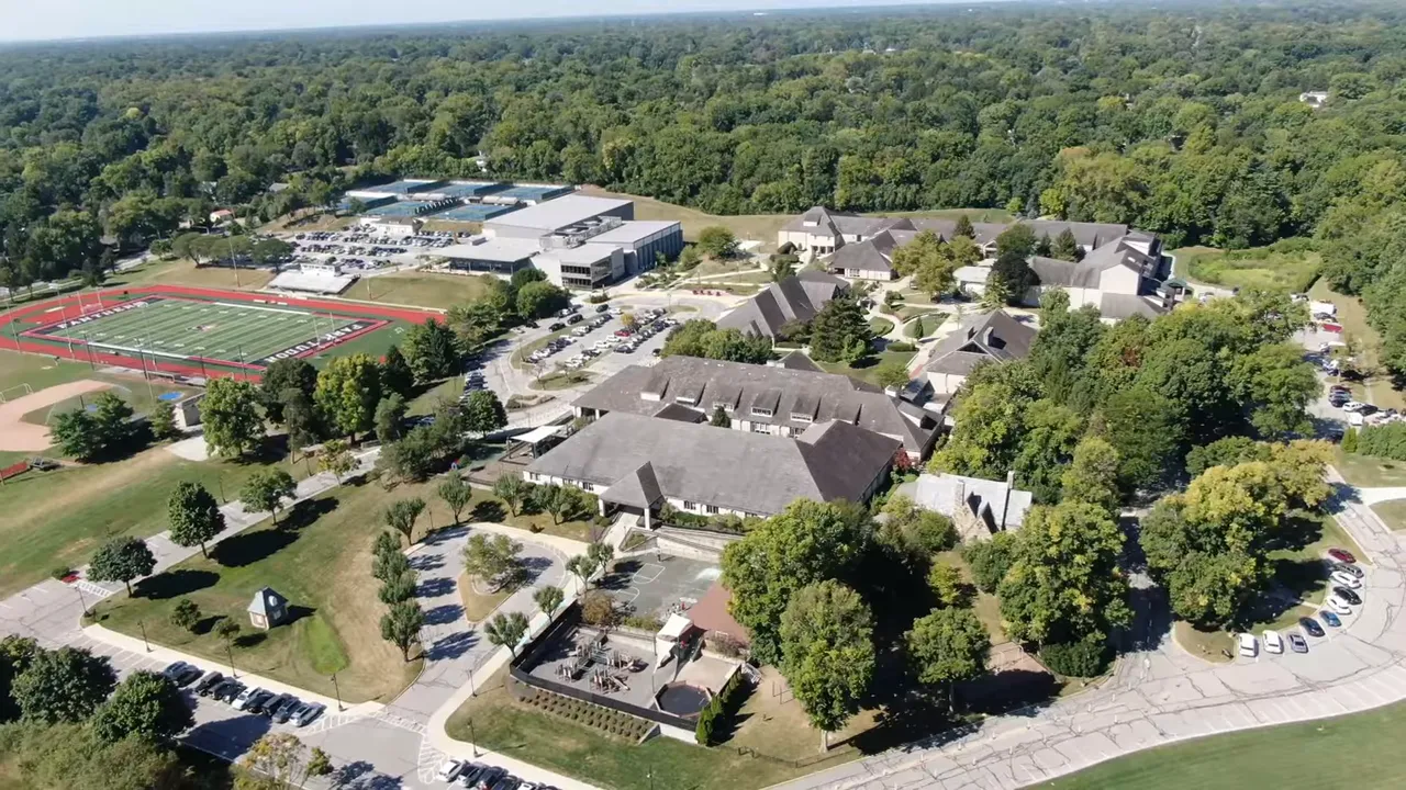 Presenter standing outside a public building with a bright QR overlay and text 'FREE RELOCATION GUIDE — SCAN HERE'.