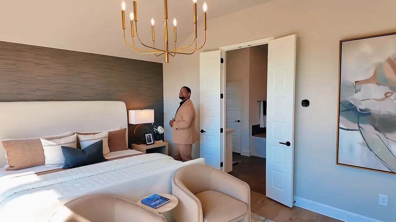 Primary suite with large bed dresser artwork and doorway to bath