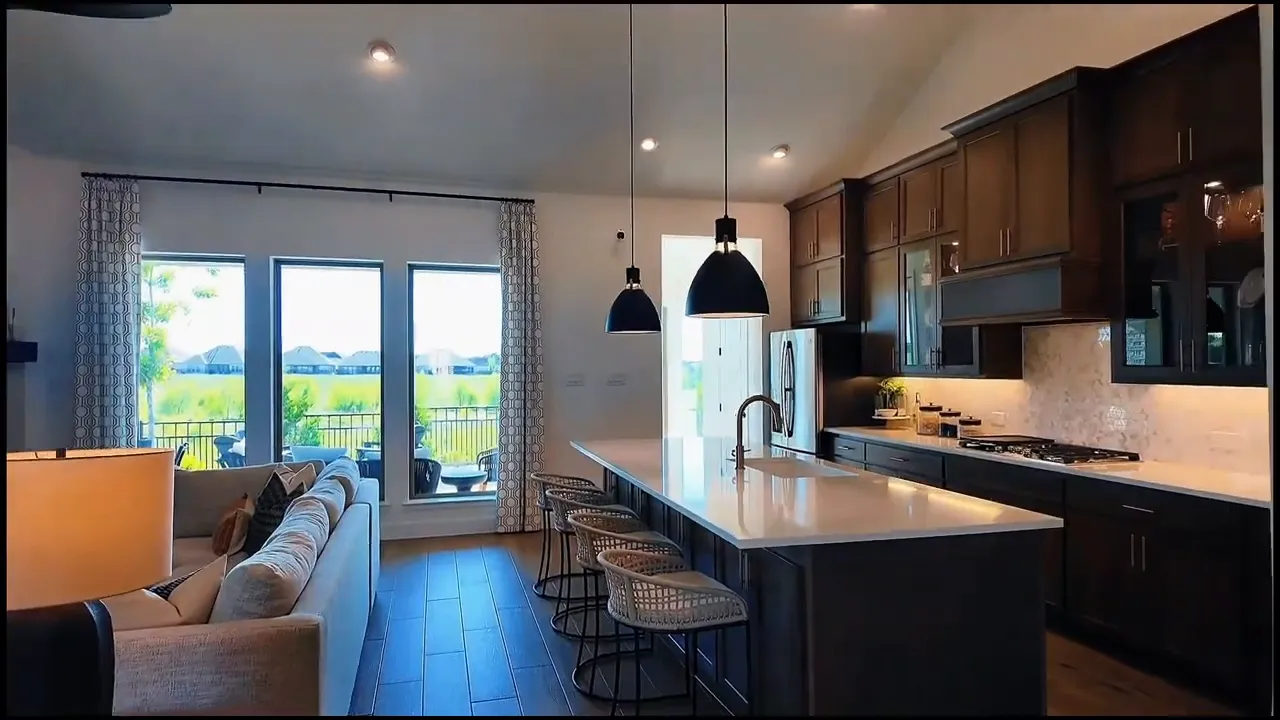 Open kitchen with large island pendant lights bar stools and living area beyond